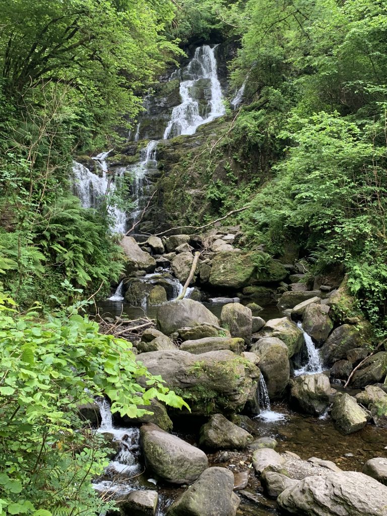 Torc Waterfall surrounded by lush forest in Killarney National Park.